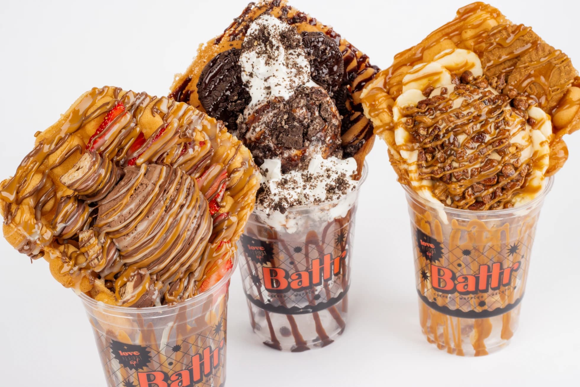 Three Battr bubble waffles in cups: chocolate gelato with strawberries, an Oreo Blast, and a Cookie Butter Fosters.