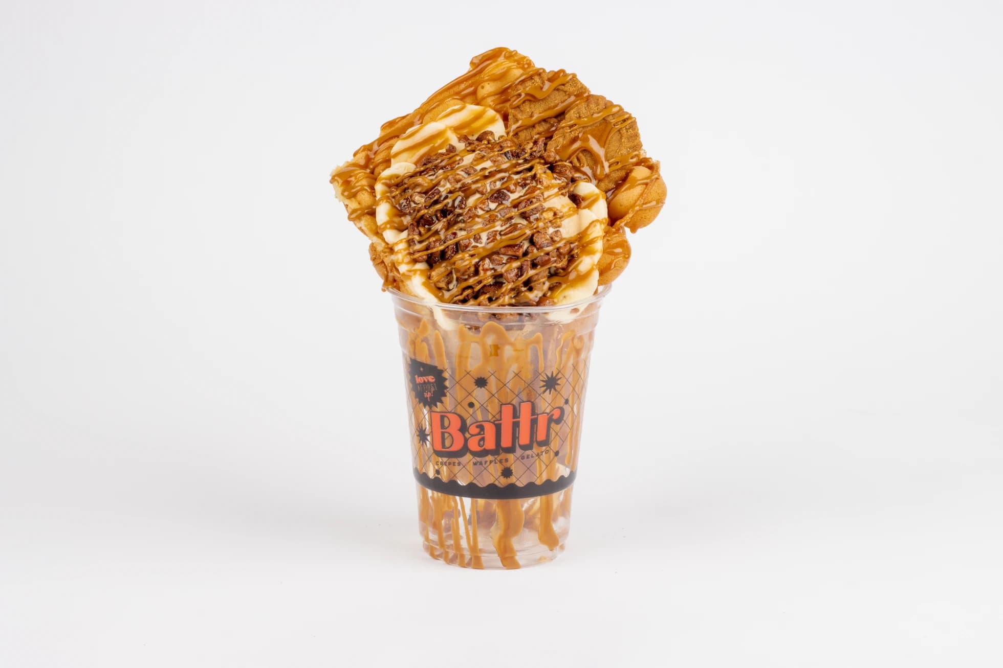 Cookie Butter Fosters bubble waffle — salted caramel gelato, sliced bananas and candied pecans under a Biscoff cookie butter drizzle, in a branded Battr cup.