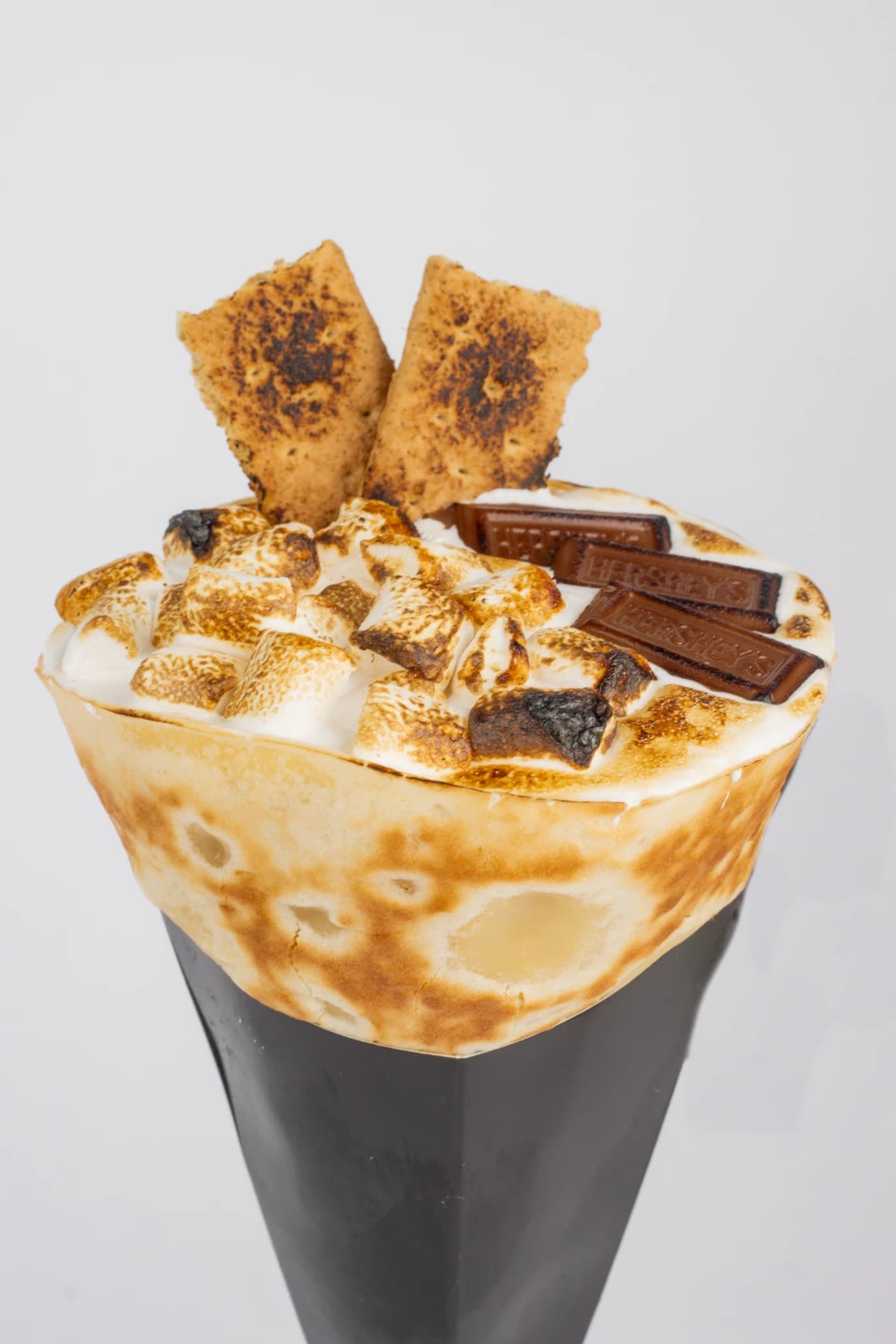 The S'More crepe cone — torched marshmallows, Hershey's chocolate bars and toasted graham crackers piled on top of a black paper cone.